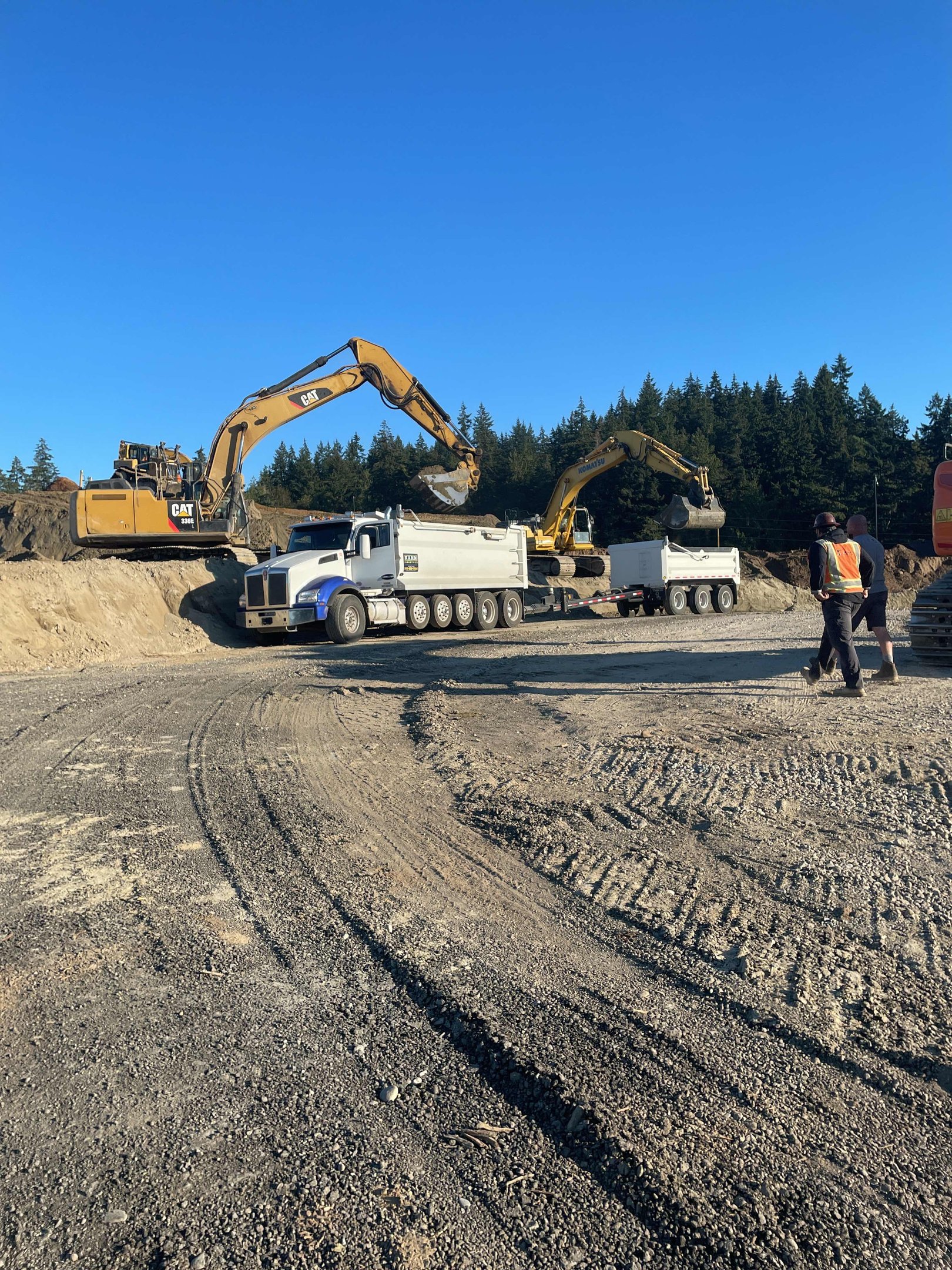 Allegiance Trucking dump trucks being loaded by excavators on a job site